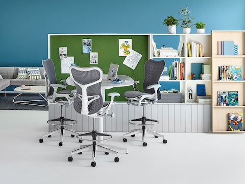 Three Mirra chairs sit at an empty table in front of shelving units. Three Mirra chairs sit at an empty table in front of shelving units.