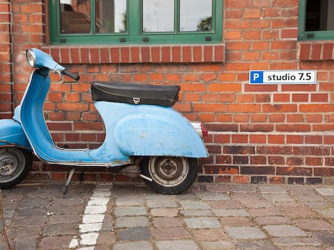 A vintage blue motorbike parked alongside the exterior brick wall of Studio 7.5 in Berlin. A vintage blue motorbike parked alongside the exterior brick wall of Studio 7.5 in Berlin.