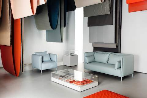 Blue ColourForm seating beneath hanging textiles of various colors. Blue ColourForm seating beneath hanging textiles of various colors.