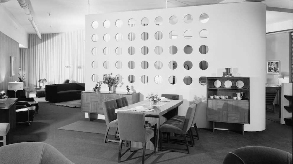 A black and white composition photo of furniture in a 1939 showroom designed by Gilbert Rohde. A black and white composition photo of furniture in a 1939 showroom designed by Gilbert Rohde.